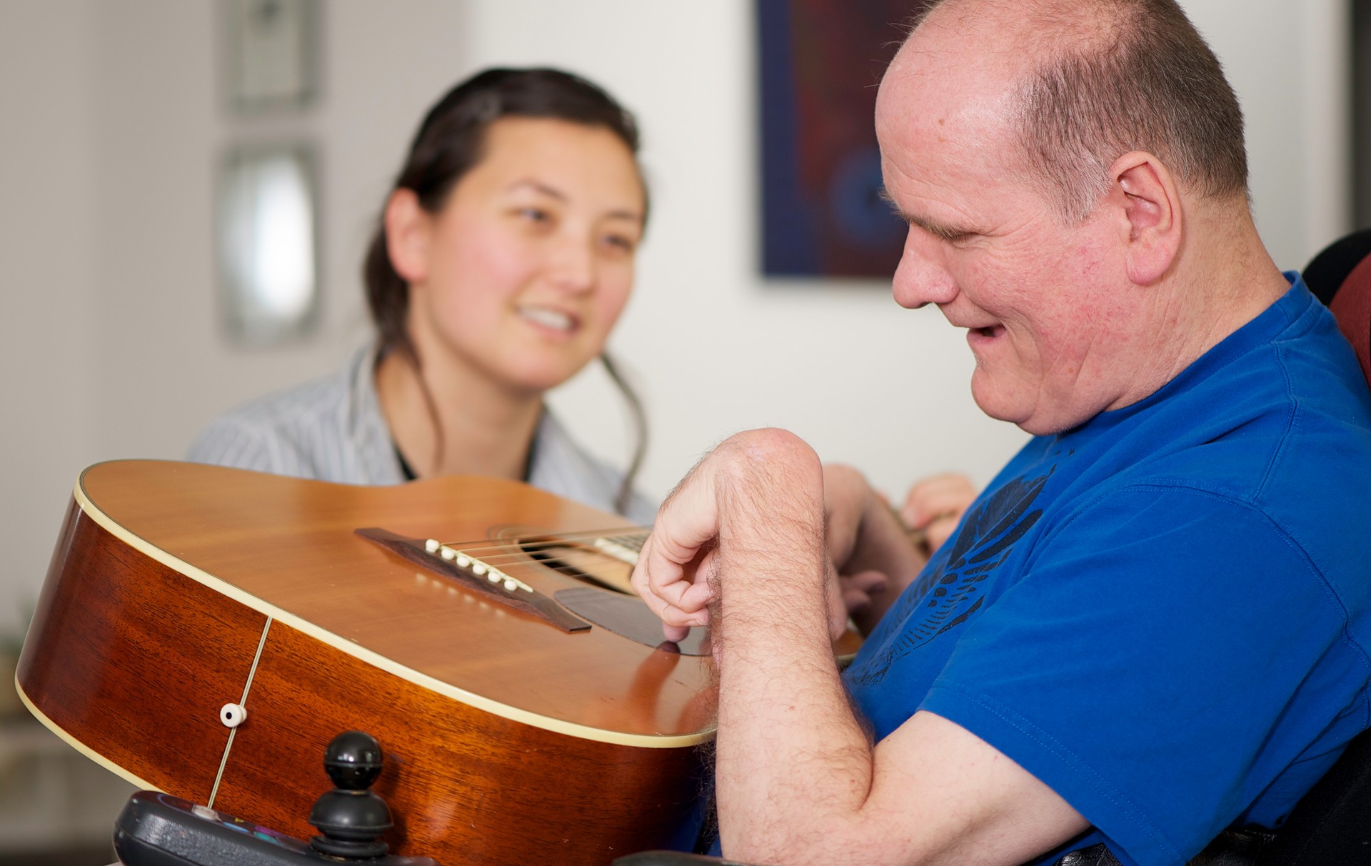 Man with disabiity, guitar, and a young woman
