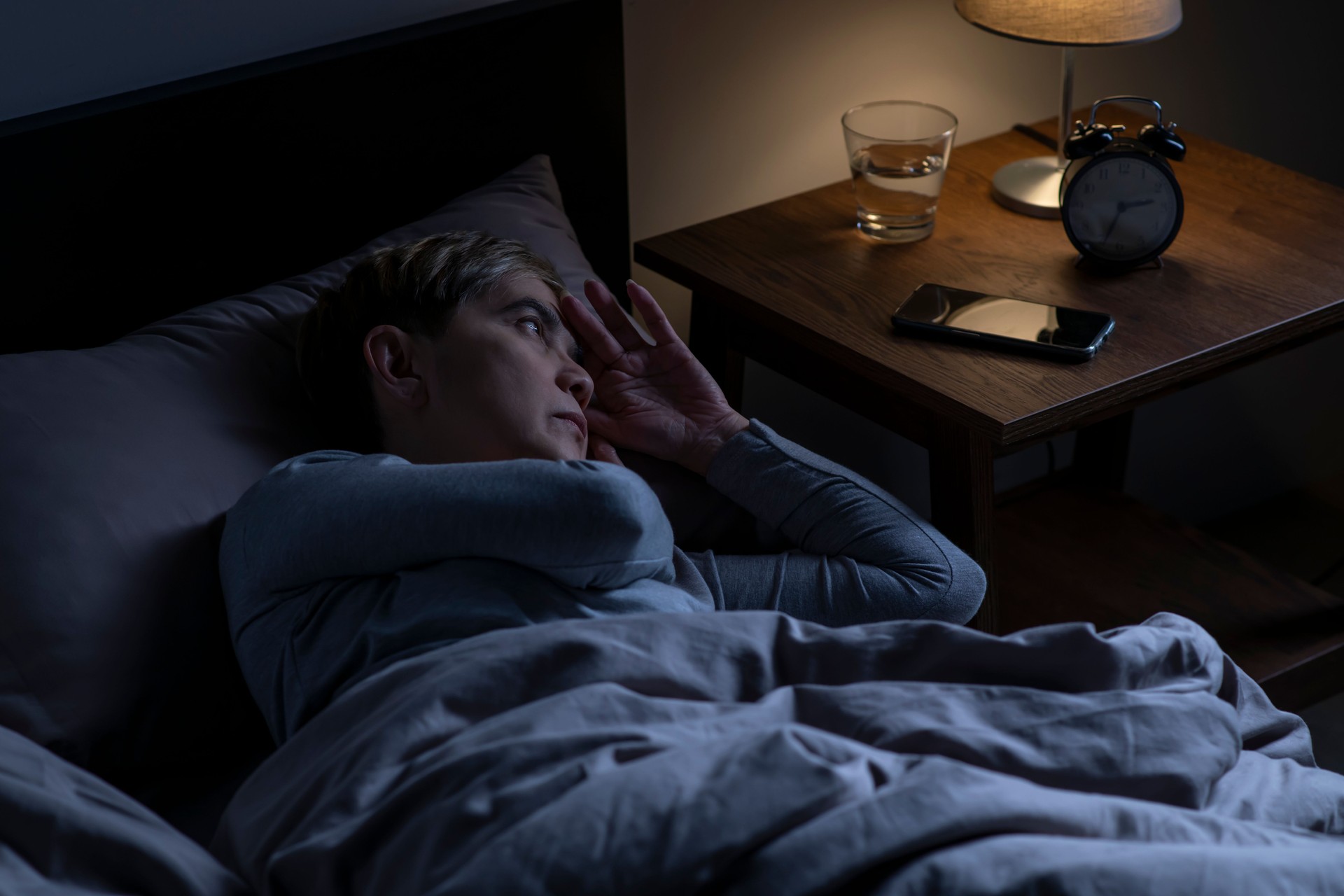 Depressed senior woman lying in bed cannot sleep from insomnia